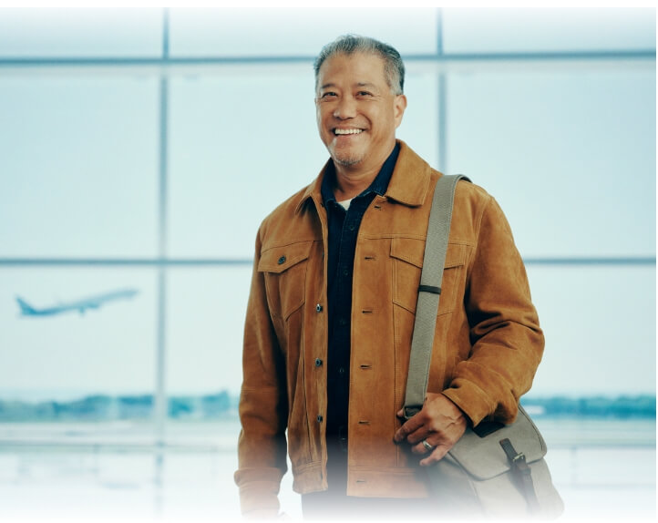 Middle-aged man smiling at camera while in airport. Not actual patient